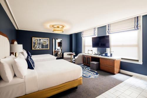 a bedroom with blue walls and a bed and a television at The National, Autograph Collection in Oklahoma City