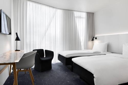 Pokój hotelowy z 2 łóżkami i krzesłem w obiekcie AC Hotel by Marriott Bella Sky Copenhagen w Kopenhadze