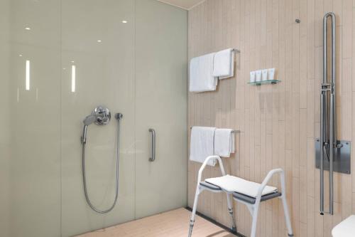 eine Dusche mit einem weißen Stuhl im Bad in der Unterkunft AC Hotel by Marriott Bella Sky Copenhagen in Kopenhagen