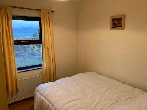 ein Schlafzimmer mit einem Bett und einem großen Fenster in der Unterkunft Glynsk Pier Cottage in Carna