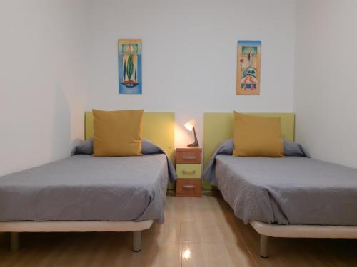 a bedroom with two beds and a night stand with a lamp at La Calma en Playa de Salinetas - cerca de playa y supermercado in Telde