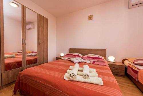 a bedroom with a bed with towels and a mirror at Apartments Delfin with seaview 100 meters from the sea - by TA Leut Agency in Privlaka
