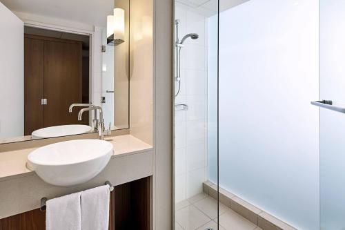 a bathroom with a sink and a glass shower at Courtyard by Marriott Sydney-North Ryde in Sydney