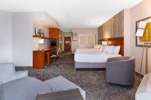 a hotel room with a bed and a desk and a couch at Courtyard by Marriott Oklahoma City Downtown in Oklahoma City
