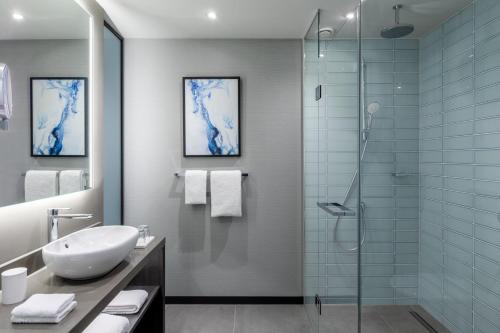 uma casa de banho com um lavatório e uma cabina de duche em vidro. em The Den, 's-Hertogenbosch, a Tribute Portfolio Hotel em Den Bosch