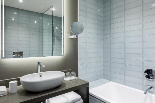 a bathroom with a white sink and a tub at The Den, 's-Hertogenbosch, a Tribute Portfolio Hotel in Den Bosch