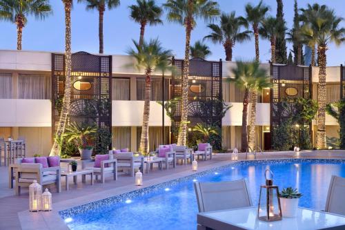 uma piscina de hotel com mesas e cadeiras e palmeiras em Amman Marriott Hotel em Amã