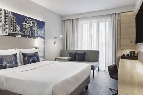 a hotel room with a large bed and a couch at Courtyard by Marriott Hamburg City in Hamburg