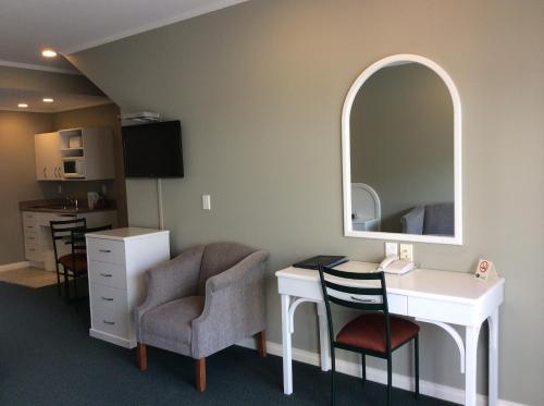 a room with a desk and a mirror and a chair at Cornwall Motor Lodge in Palmerston North