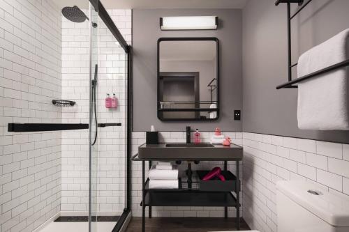 納許維爾的住宿－Moxy Nashville Vanderbilt Area，浴室配有盥洗盆和带镜子的淋浴