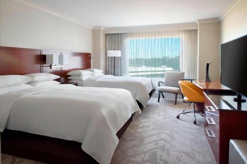 a hotel room with four beds and a television at Atlanta Airport Marriott Gateway in Atlanta