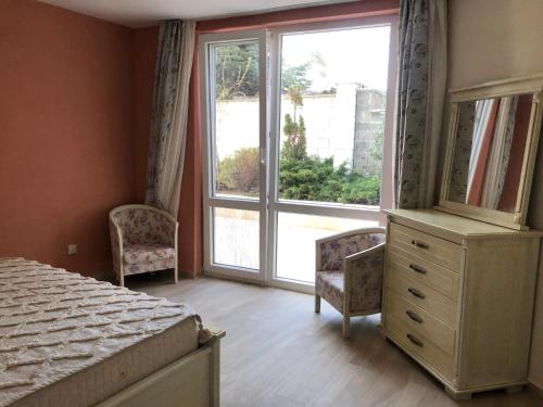 a bedroom with a bed and two chairs and a window at Морска Роза in Sinemorets