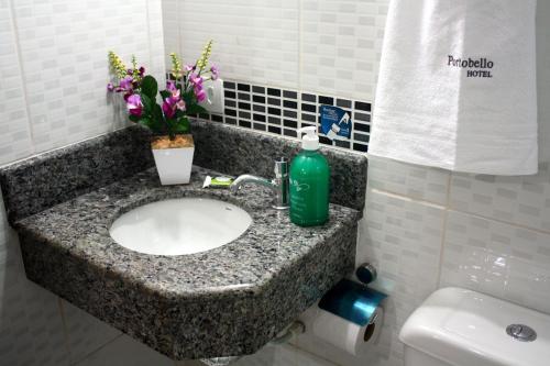 a bathroom sink with a green soap bottle on it at Hotel Portobello in Aparecida