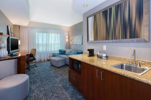 een hotelkamer met een wastafel en een woonkamer bij Courtyard Omaha La Vista in La Vista