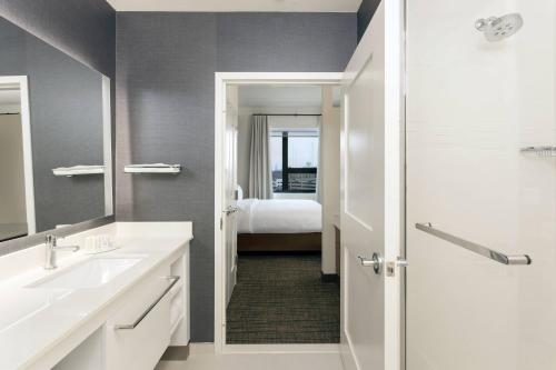 een badkamer met een wastafel en een slaapkamer met een bed bij Residence Inn By Marriott Philadelphia Bala Cynwyd in Bala-Cynwyd