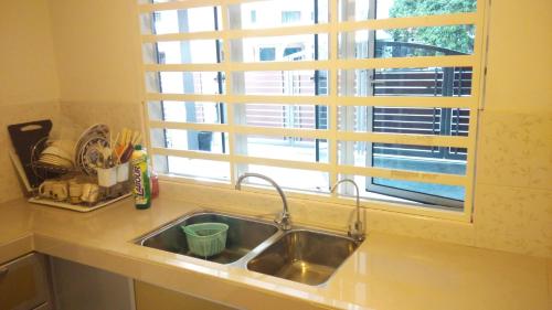 a kitchen sink with a window above it at Bercham Vacation House in Ipoh