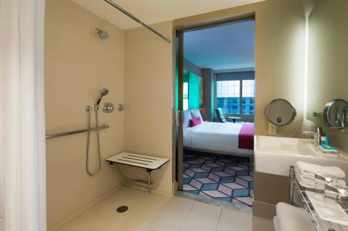 a bathroom with a shower and a bed and a sink at W New York - Times Square in New York