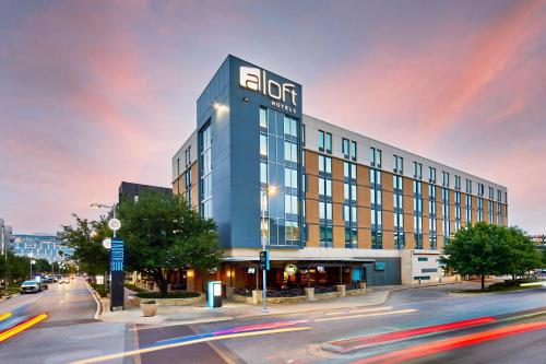 a building on a street with cars driving past it at Aloft Austin at The Domain in Austin