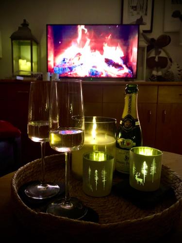 two glasses of wine and candles on a table with a television at FeWo Fuchs Saig in Lenzkirch