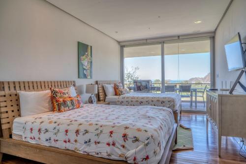 a bedroom with two beds and a tv and a balcony at Altos de Montserrat 2 1 in Herradura