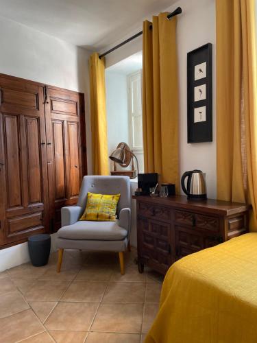 a bedroom with a chair and a dresser and a bed at Casa Aire de Lecrin in Pinos del Valle