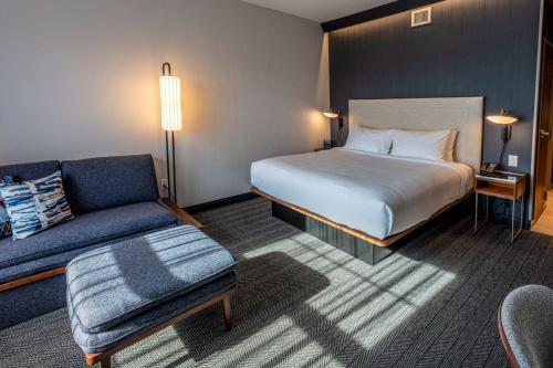 a hotel room with a bed and a couch at Courtyard Rochester Downtown in Rochester