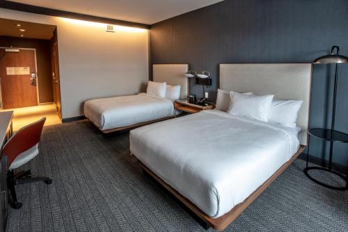 a hotel room with two beds and a desk at Courtyard Rochester Downtown in Rochester