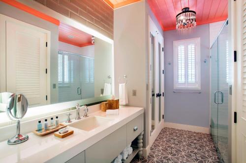 a bathroom with a sink and a mirror and a shower at French Leave Resort, Autograph Collection in Governorʼs Harbour