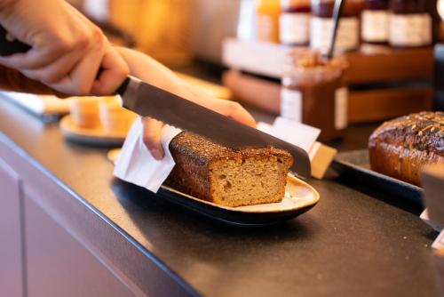 a person cutting a piece of bread with a knife at ibis Styles Montauban in Montauban