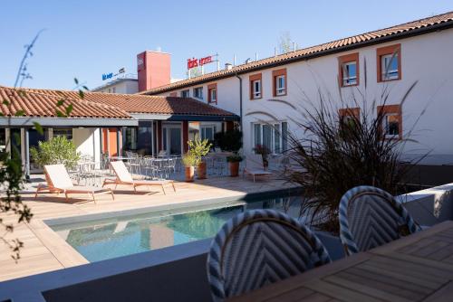 un patio con sillas y una piscina frente a un edificio en ibis Styles Montauban en Montauban