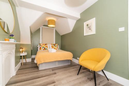 1 dormitorio con 1 cama y 1 silla amarilla en [Olympia-Museums-Kensington]London Apartment, en Londres