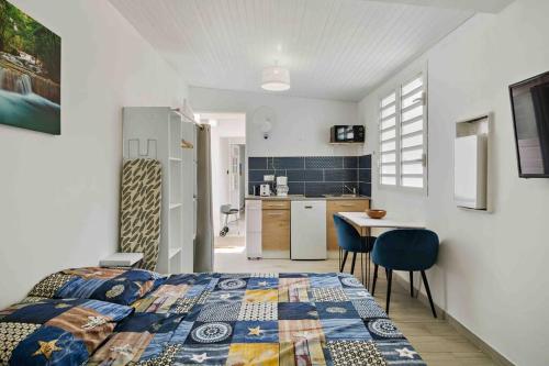a bedroom with a bed and a table and a kitchen at Le Camélia - Résidence Terre et Truffes in Le Lamentin