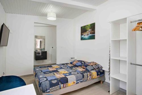 a bedroom with a bed and a white wall at Le Camélia - Gîte "Terre et Truffes" in Le Lamentin