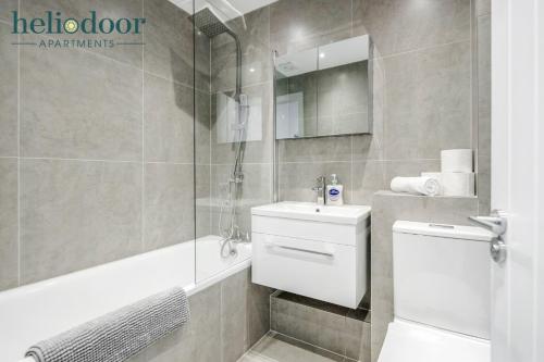 La salle de bains est pourvue de toilettes, d'un lavabo et d'une douche. dans l'établissement HAML Heliodoor Apartments Milton Keynes, Free Parking, Free WiFi & Movies, 7-min drive to City Centre, à Wolverton