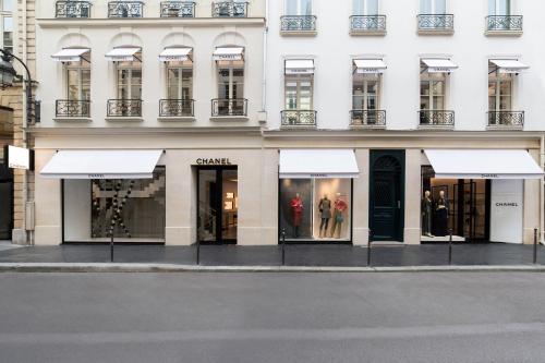 Chic Apartment on the famous shopping Rue du Faubourg Saint-Honoré street في باريس: متجر أمام مبنى به مظلات بيضاء