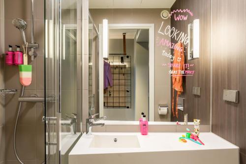 a bathroom with a sink and a mirror at Moxy Berlin Airport in Schönefeld