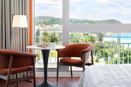 a hotel room with a bed and a table and chairs at Le Meridien Nice in Nice