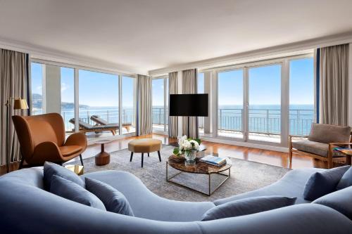 a living room with a blue couch and large windows at Le Meridien Nice in Nice