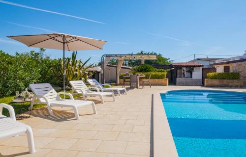 a group of chairs and an umbrella next to a swimming pool at Villa Mariant con Piscina Privata in Ruffano