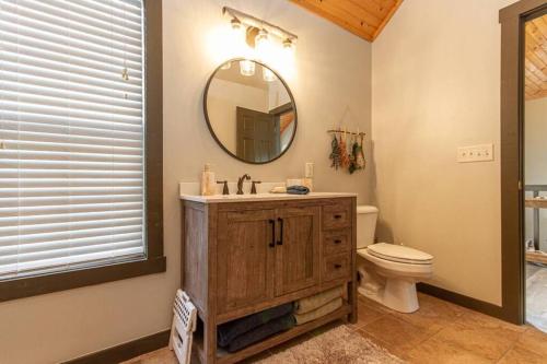 a bathroom with a sink and a toilet and a mirror at Gorgeous cabin 3bdrm/3bth, hot tub, fireplace, kid/pet friendly in Galena