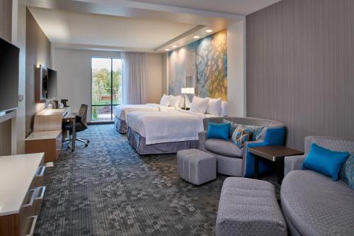 a hotel room with a bed and a desk and a couch at Courtyard by Marriott Petoskey at Victories Square in Petoskey