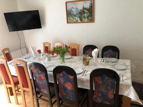 a dining room table with a white table cloth and chairs at Dom pod barankiem in Mielno