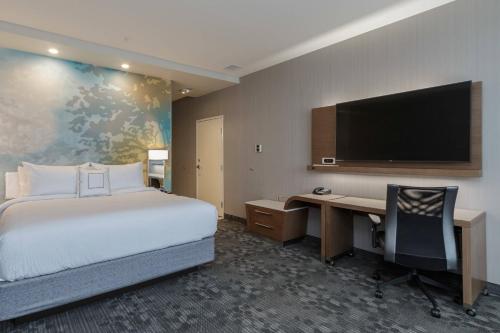 a hotel room with a bed and a desk and a tv at Courtyard by Marriott South Bend Downtown in South Bend
