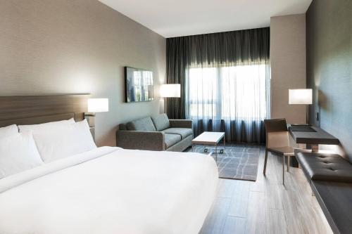 ケンブリッジにあるAC ホテル バイ マリオット ボストン ケンブリッジの白い大型ベッドとソファが備わるホテルルームです。