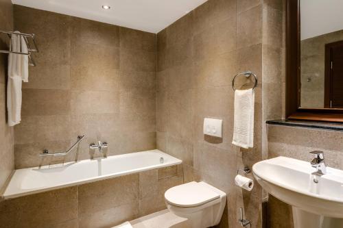 a bathroom with a tub and a toilet and a sink at Protea Hotel by Marriott Owerri Select in Owerri