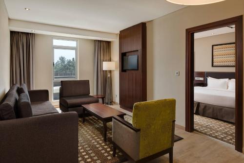 um quarto de hotel com uma cama e uma sala de estar em Protea Hotel by Marriott Owerri Select em Owerri