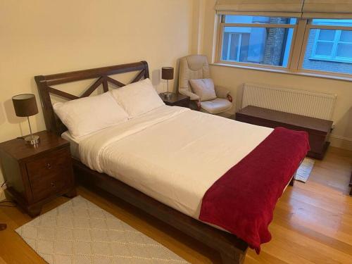a bedroom with a large bed and a chair at Luxurious serviced apt next to the City of London and Tower Bridge in London