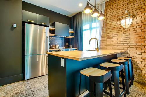 a kitchen with a refrigerator and a counter with stools at Les Lofts de la Gare - Par Les Lofts Vieux-Québec in Quebec City