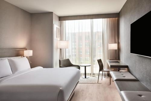 チェスターフィールドにあるAC Hotel by Marriott St Louis Chesterfieldのベッドと大きな窓が備わるホテルルームです。