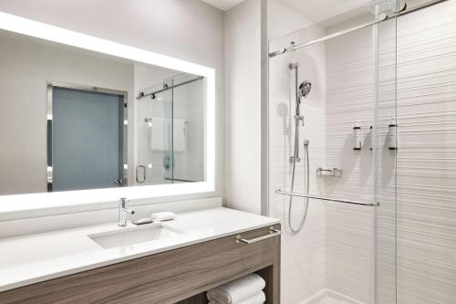 a white bathroom with a sink and a shower at AC Hotel by Marriott St Louis Chesterfield in Chesterfield